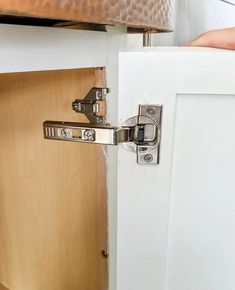 a close up of a door handle on a white cabinet with a brown leather bag in the background