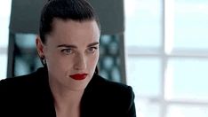 a woman with dark hair and red lipstick looks at the camera while wearing a black jacket