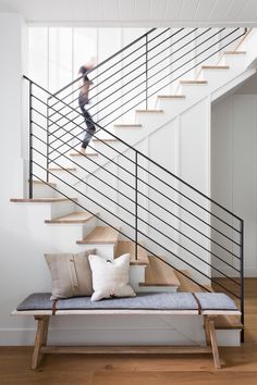 a person is walking down the stairs in a house with white walls and wood floors