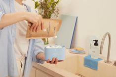 a woman holding a brown paper bag over a sink