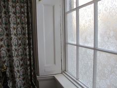 an open window in a bathroom next to a shower curtain and toilet paper dispenser