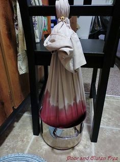 a vase sitting on top of a wooden table next to a black chair with a red and white tie dye design