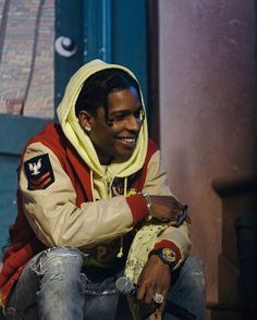 a young man sitting on the ground wearing a yellow hoodie