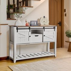 a white table with drawers under a stair case next to a clock and potted plant