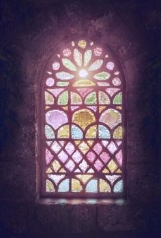 an old stained glass window in a stone building with light coming through it's windows