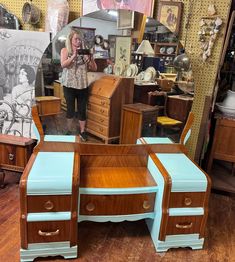 a woman standing in front of a blue and brown desk with two drawers on it