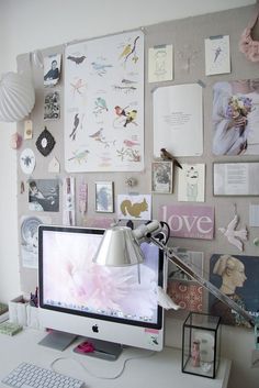 a desktop computer sitting on top of a desk next to a lamp and pictures hanging on the wall