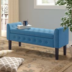 a blue bench sitting on top of a rug in a living room next to a potted plant