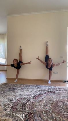 two girls are doing yoga in front of a wall with their hands up and one girl is standing on her knees