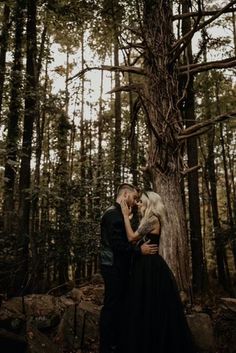 a man and woman standing next to each other in the woods