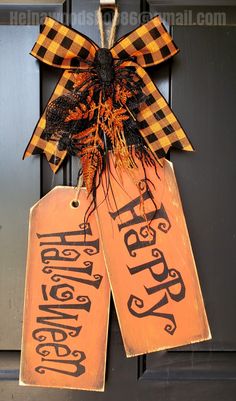 two wooden tags with happy halloween written on them hanging from the front door, decorated with black and orange plaid ribbon