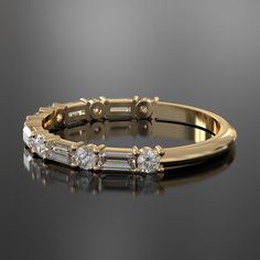 a yellow gold ring with five baguettes and three diamonds on the side, sitting on a black surface