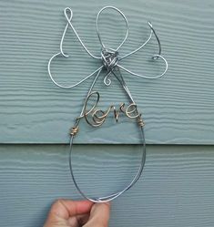 a hand holding a wire sculpture with the word love in it's center, on a blue background