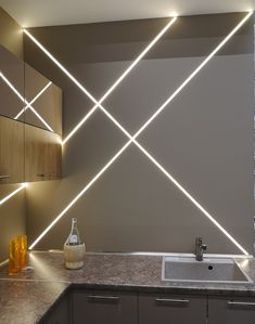 a kitchen counter with a sink and some lights on the wall in front of it