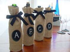 three burlap wine bottles with black ribbon and monogrammed labels on them