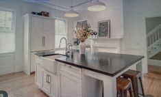 an image of a kitchen setting with white cabinets and black counter tops, along with stools