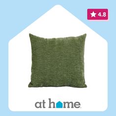 a green pillow sitting on top of a blue and white sign that says at home