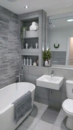 a white bath tub sitting next to a toilet under a bathroom mirror in a bathroom