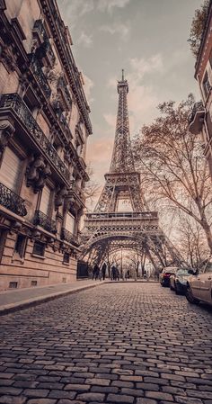 the eiffel tower in paris, france is seen from an old cobblestone street