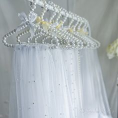 a white dress with pearls and bows hanging from it's hangers on the wall