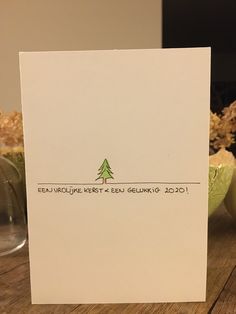 a white card with a green christmas tree on it sitting on a table next to some vases