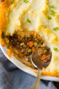 a close up of a spoon in a bowl filled with mashed potatoes and meat