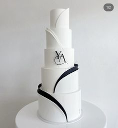 a three tiered white cake with black ribbon around the bottom and an aa logo on top