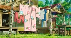 clothes hanging out to dry in front of a wooden cabin with trees and grass on the ground