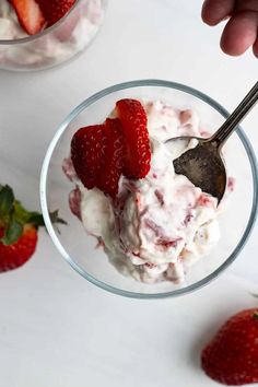 someone spooning strawberries into a bowl of ice cream