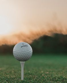 a golf ball sitting on top of a white tee in the middle of a field