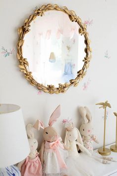 some stuffed animals and a mirror on a white wall in a room with pink flowers