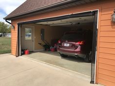 a car is parked in the garage with its door open and luggage on the floor