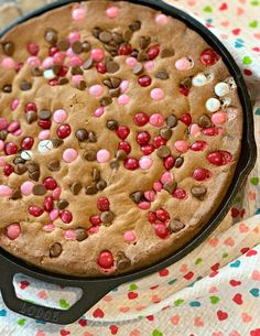 a chocolate chip cookie with pink and brown sprinkles on it sitting in a cast iron skillet