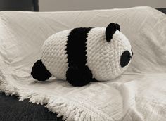 a crocheted panda bear laying on top of a bed