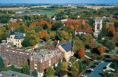 an aerial view of a college campus surrounded by autumn trees and grass in the foreground