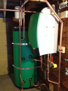 a large green tank sitting inside of a building next to pipes and piping hoses