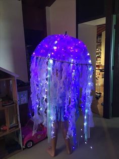 a child standing in front of a purple jellyfish tent with blue lights on it