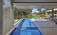 an indoor swimming pool in the middle of a house with lounge chairs and sun shades