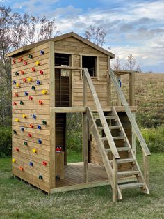 there is a small wooden structure with a ladder to the top and a climbing wall