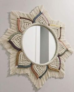 a mirror that has some tassels on it and is hanging on the wall