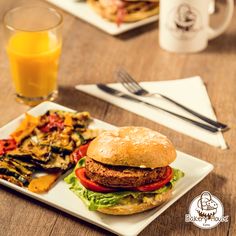 a plate with a burger and fries on it next to a glass of orange juice