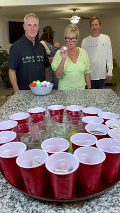 a group of people standing around a table with cups on it