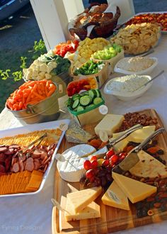 an assortment of cheeses, crackers and vegetables on a table