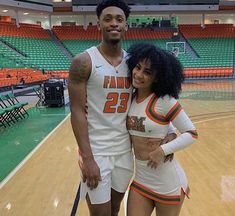 a man and woman in cheerleader outfits standing on a basketball court