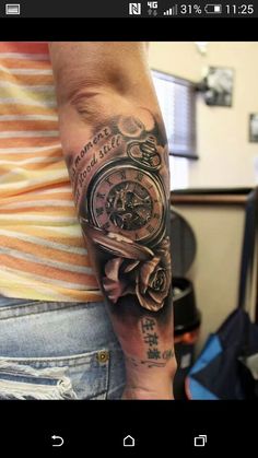 a person with a clock and roses tattoo on their arm is holding a cell phone