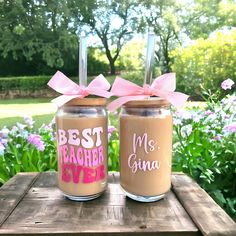 two mason jars with the words best teacher ever and pink bows are sitting on a picnic table