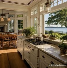 a kitchen with an island, stove top oven and lots of windows overlooking the water