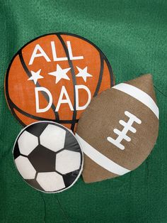 an all dad football, basketball and soccer ball on green fabric