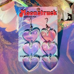 three heart shaped earrings are hanging from a card with the moontruck logo on it