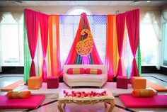 a decorated room with pink and orange drapes, white couches, and tables